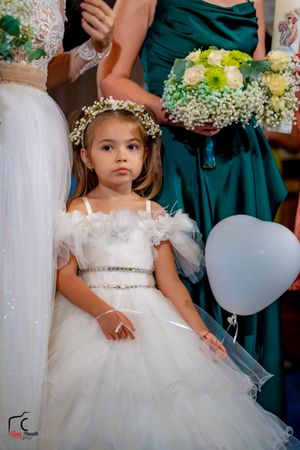 Young attendant in white tulle dress with floral crown at formal event.
