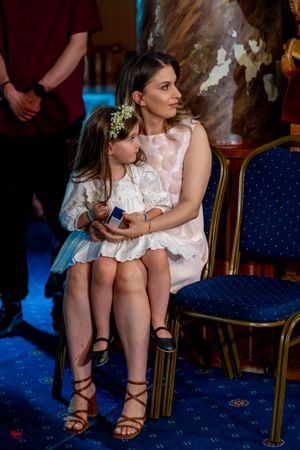 Close-up of sandaled feet and white dresses on blue carpeting during a wedding ceremony.