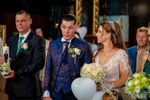 Wedding party stands together holding bouquets and wearing formal attire during the ceremony.