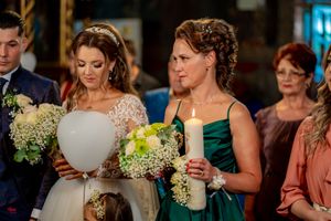 Wedding party members hold white bouquets and candles during a traditional ceremony.