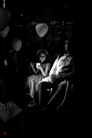 Dramatic black and white photo of two people sitting in darkness with a white balloon casting soft illumination.
