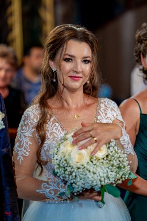 A wedding celebration showing a beautiful bouquet of white roses and baby's breath with lace dress details.
