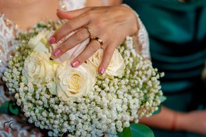 Wedding rings showcased against a delicate bouquet of white roses and baby's breath flowers.