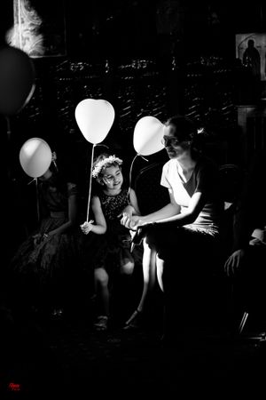 Black and white photo of guests playing with white balloons at a party.
