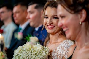 Wedding attendees smile and celebrate during indoor reception with elegant lighting.