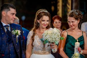 Wedding party members stand together during indoor reception with atmospheric lighting.