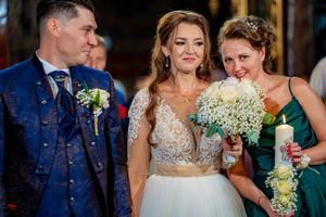 Candid wedding moment shared between couple and bridesmaid in church setting.