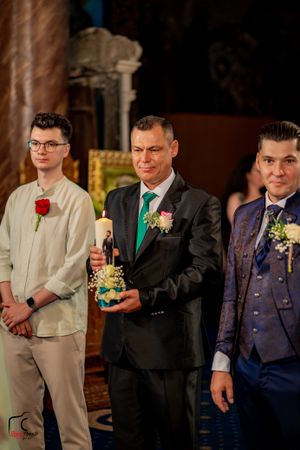 Groomsmen in dark suits and light vests pose during wedding reception.