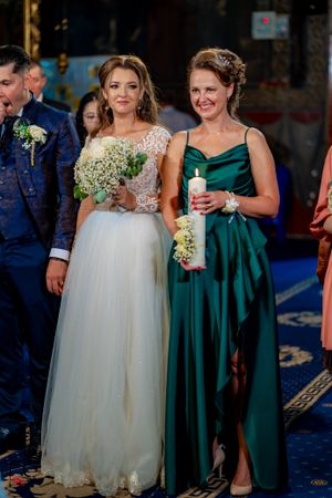 Bridesmaids in emerald green dresses stand with bride in white gown during reception.