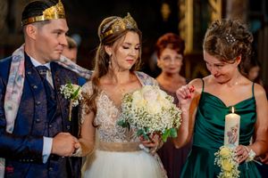 Wedding party members in formal attire holding lit candles during traditional ceremony.