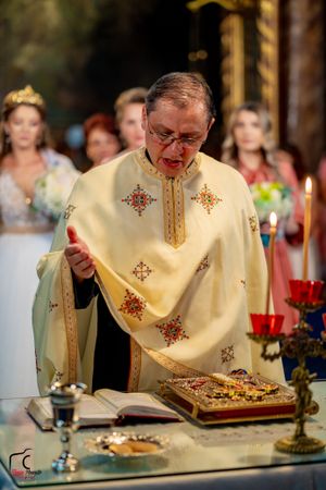 Priest in cream-colored vestments with ornate cross embroidery conducts religious ceremony at altar.