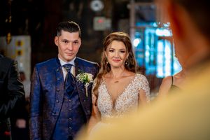 Wedding party members pose during celebration in an ornate indoor setting with dramatic lighting.