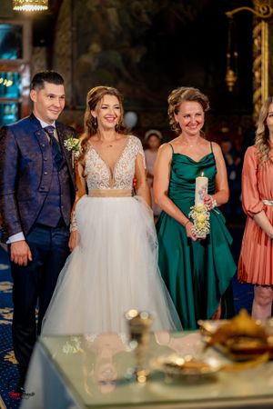 Wedding party poses together in an ornate venue with blue carpeting and golden decorative elements.