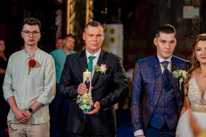 Wedding party members in formal attire gather at an elegant indoor venue with blue carpet and ornate decor.