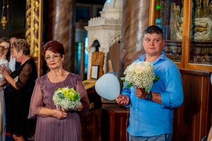 Wedding party members gather in a church interior with traditional wooden furnishings.