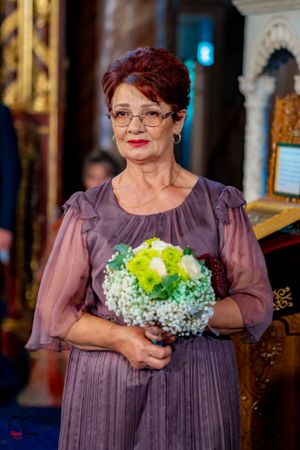 A wedding guest in a purple dress holds a bouquet with green and white flowers.