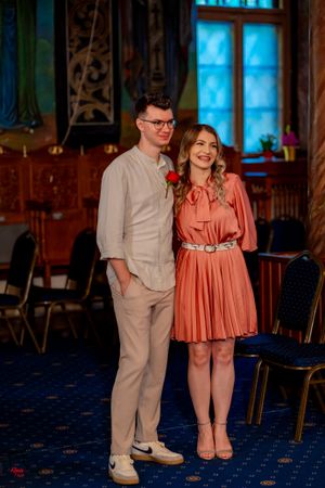 Couple in coral and white outfits dancing on blue carpeted floor.