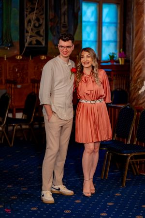 Couple in formal attire dancing on blue carpeted floor with blue-lit windows.