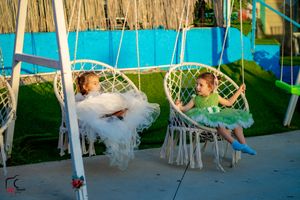 Outdoor wedding venue with bohemian-style hanging chairs and natural bamboo wall decor.