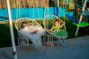 Outdoor wedding reception setup with macrame hanging chairs and rustic decor against a bamboo backdrop.