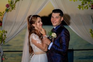 A wedding couple poses under a floral arch with a painted backdrop.