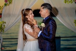 Wedding couple shares intimate moments under a floral arch by the water.