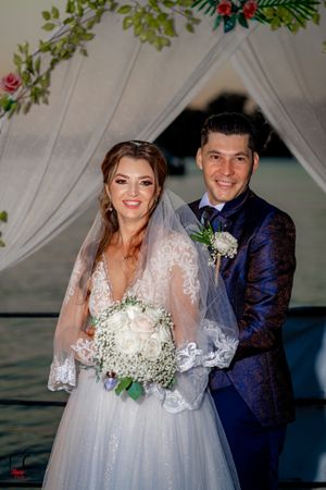 Wedding portraits captured under a decorated arch with white draping and florals at dusk.
