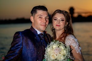Elegant wedding couple posing on boat with white baby's breath bouquet at dusk.