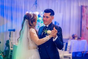 Couple sharing their first dance at a wedding reception under blue ambient lighting.