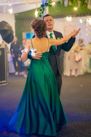 Dancing couple in formal wear performing under ambient lighting with decorative elements.
