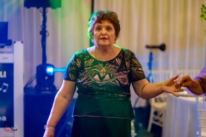 Dancer in green patterned dress participating in group dance at indoor celebration.