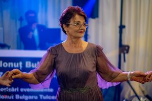 Dancer in purple dress performing traditional moves at an indoor event.