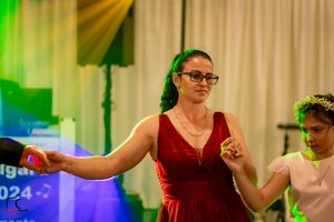 Dance participants moving enthusiastically during a choreographed routine under colored lights.
