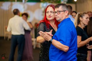 Dance partners moving gracefully across a brightly lit indoor venue during a social gathering.