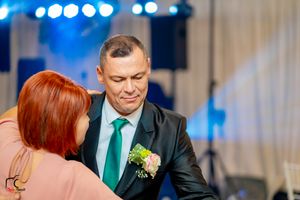 Formal dance partners moving gracefully at an evening event with blue stage lighting.