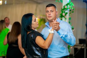 Partners dancing together during a formal evening event with decorative lighting.