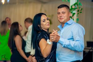 Couples dancing in an indoor venue decorated with greenery and soft lighting.