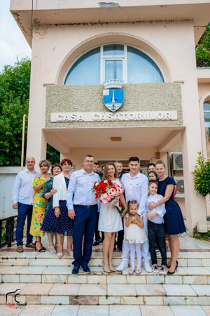 Large group poses for formal photo outside building entrance with arched doorway.