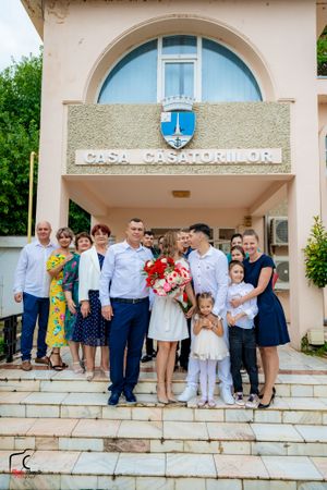 Celebratory group photo taken outside Casa Casatoriilor building with stone steps.