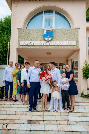 People gather for a photo on stone steps outside a building with an arched entrance.