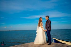 Seaside wedding photography session featuring a couple on a wooden pier overlooking calm waters.