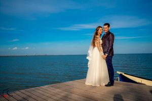 Newlyweds share intimate moments during their photoshoot on a coastal dock with ocean views.