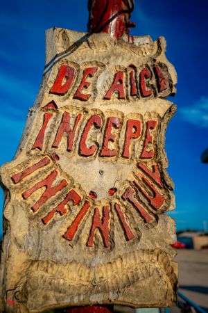 Weathered stone sign with red lettering against deep blue sky background.