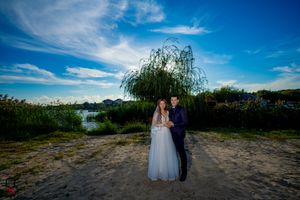 Wedding photography in natural setting with willow trees and open field at sunset.