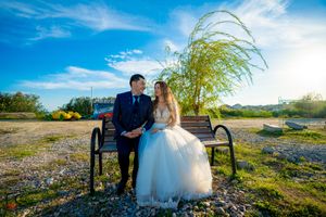 Scenic spring wedding portrait with couple on bench under willow tree branches.