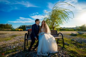 Panoramic view of newlyweds resting on park bench amid blooming spring landscape.