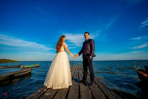 Panoramic wedding photography on a seaside dock with dramatic blue sky and ocean views.