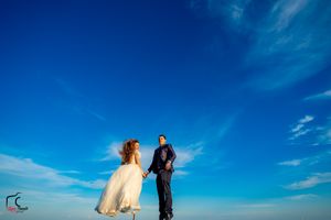 A scenic wedding photo shoot on a wooden dock overlooking calm waters under bright blue skies.