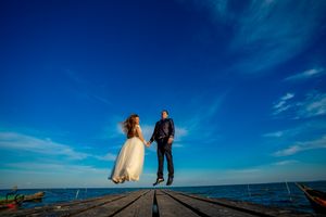 Dramatic silhouettes on seaside pier against brilliant blue sky and ocean backdrop.