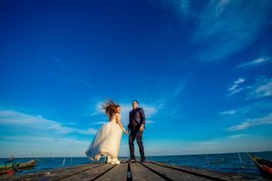 Wedding photography session on oceanfront dock with stunning blue sky composition.